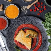 Pan Superfood-Strudel angerichtet mit Sauce auf einem schwarzem Teller