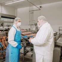 Zwei Männer mit Hygienekleidung besprechen in der Produktion eine Checkliste 