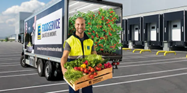 Mann mit Gemüsekiste steht vor einem EDEKA Foodservice LKW