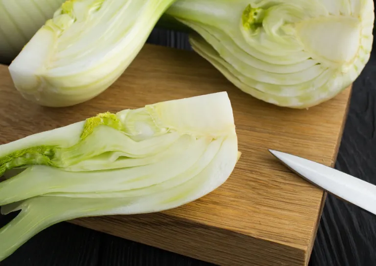 Aufgeschnittener Fenchel auf einem Holzbrett auf dem an der Seite noch das Messer liegt