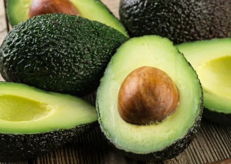Mehrere Avocados geschlossen und aufgeschnitten auf einem Tisch nebeneinander