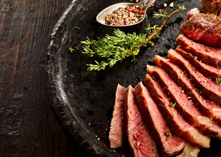 Steak mit Kaffee-Rub, aufgeschnitten auf einem dunklen Teller angerichtet