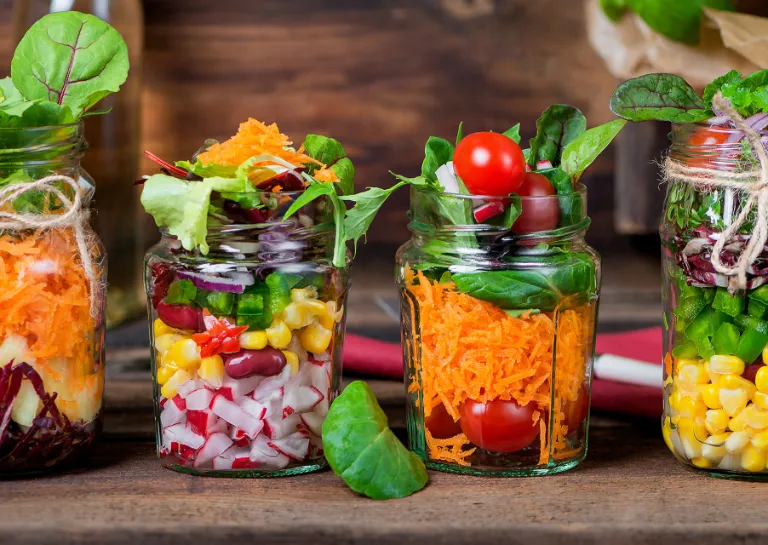 Frühlingssalate frisch aus dem Glas auf einem Holztisch