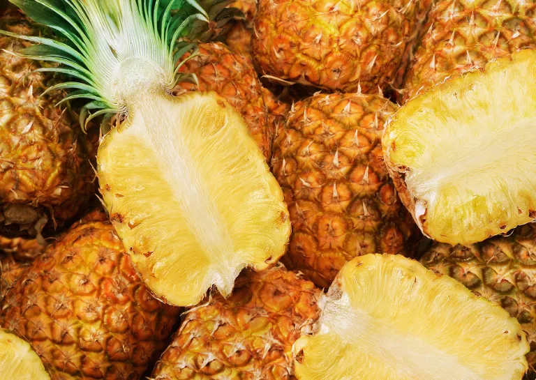 halbe und ganze Ananas liegen.