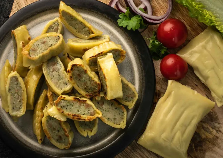 Maultaschen in streifen geschnitten und angebraten, angerichtet auf einem Teller mit frischen Tomaten
