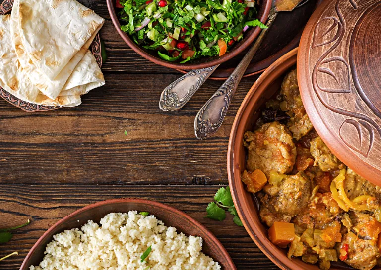 Verschiedene marokkanische Speisen auf einem Holztisch angerichtet mit Tajine.