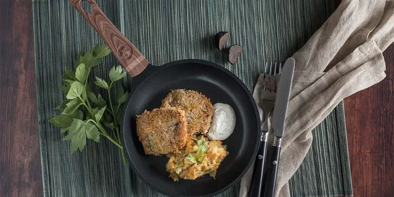 Hirschschnitzel liegt mit Mayonnaise und Wurzelgemüsestampf in einer Pfanne