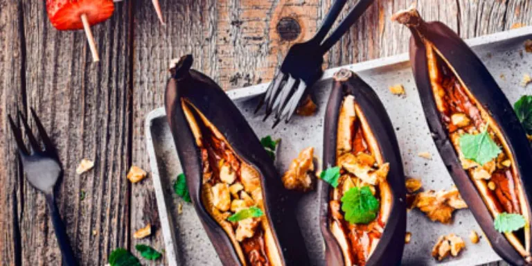 Auf einem Tablett liegen drei gegrillte Bananen gefüllt mit Schokolade