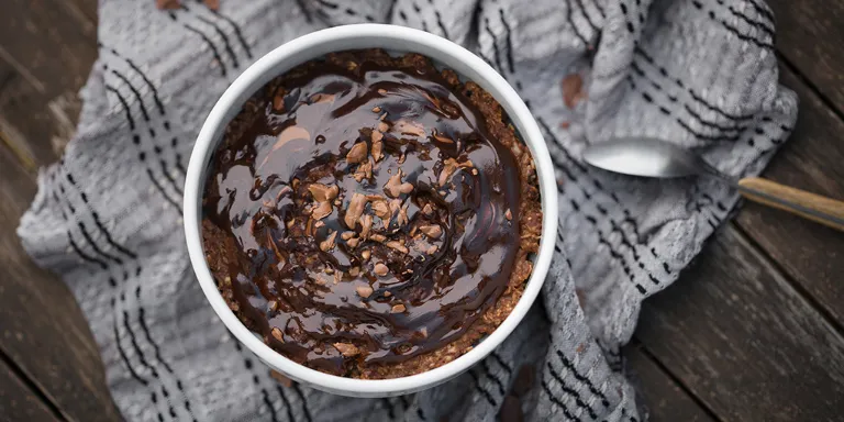 Angerichtetes Schokoladenporridge mit Datteln und Walnüssen auf einem Esstisch