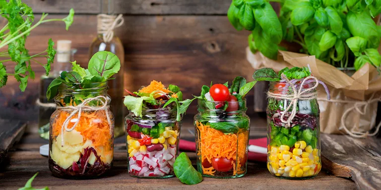 Verschiedene Salate in Weckgläsern auf einem Holzbrett