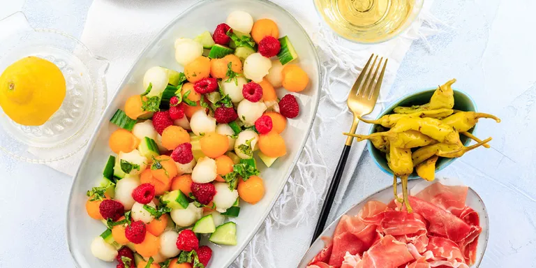 fruchtiger Sommersalat mit Melone, Himbeeren, Gurke und Petersilie. 