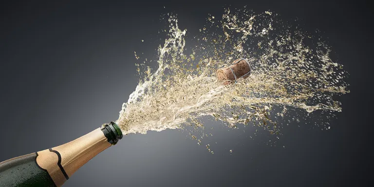 Champagnerflasche aus der Champagner spritzt und der Korken wegfliegt