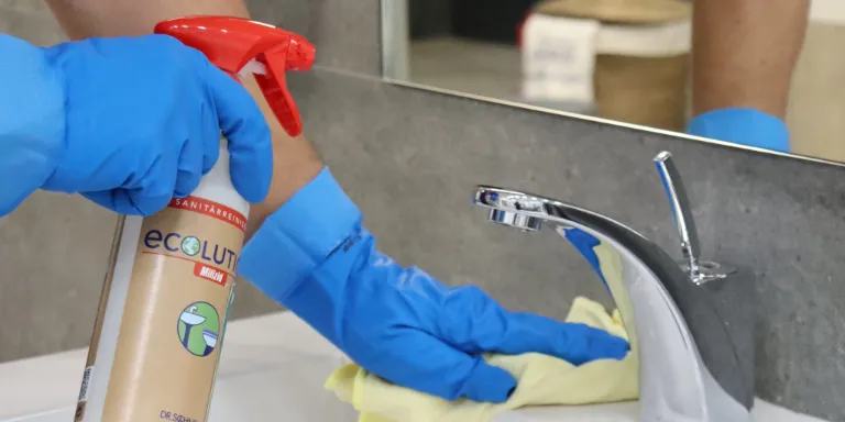Reinigung des Sanitärbereiches mit dem DR.SCHNELL-Klassiker MILIZID  - in  blauen Handschuhen