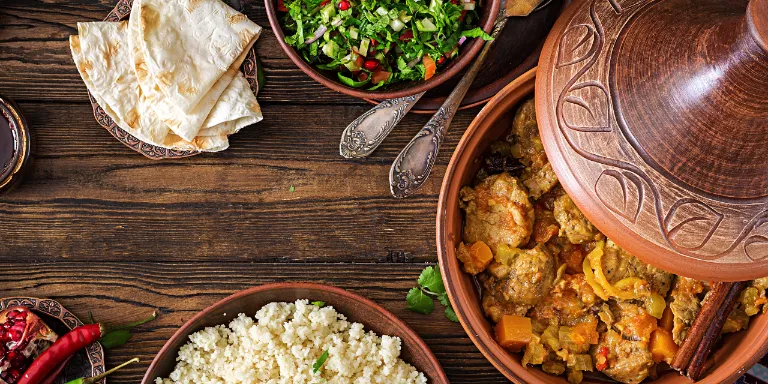 Verschiedene marokkanische Speisen auf einem Holztisch angerichtet mit Tajine.