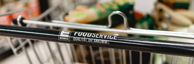 Mit Lebensmittel gefüllter Einkaufswagen. Auf der Handhabe steht EDEKA Foodservice.