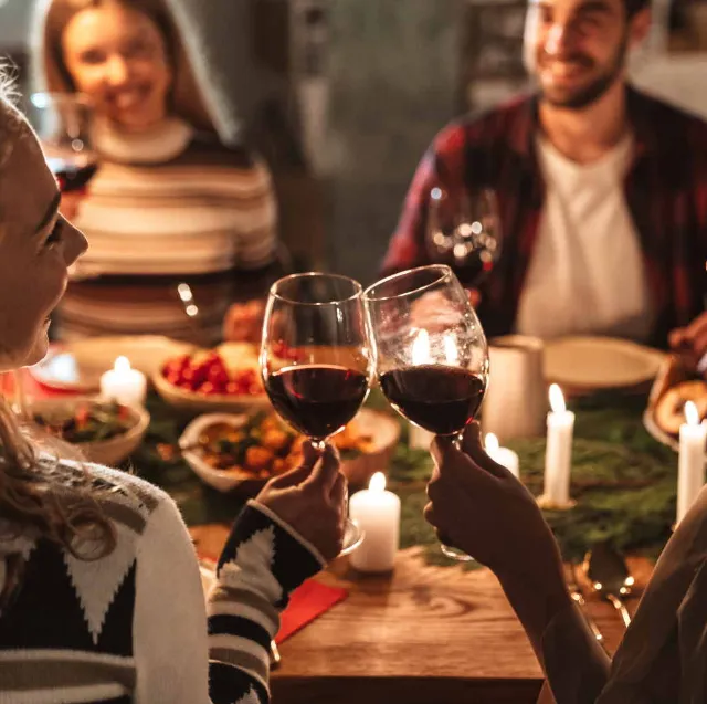 4 Personen stoßen mit Wein beim Essen an