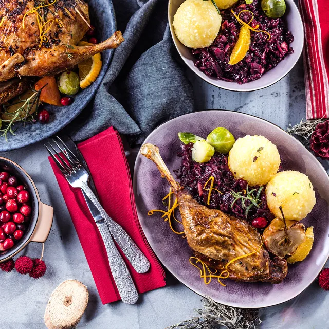 Gänsekeule mit Klößen und Rotkraut in einer grauen Schüssel angerichtet