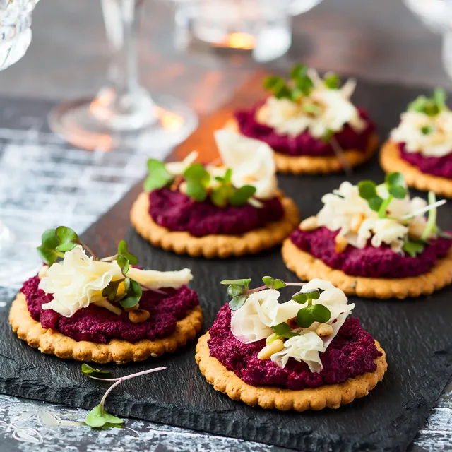 Cracker mit Rote Bete-Paté und mit Parmesan garniert auf einer Schieferplatte
