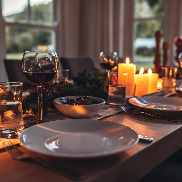 nachhaltig gedackte weiuhnachtstafel mit Kerzen, Tannengrün und weißem Geschirr sowie Gläsern