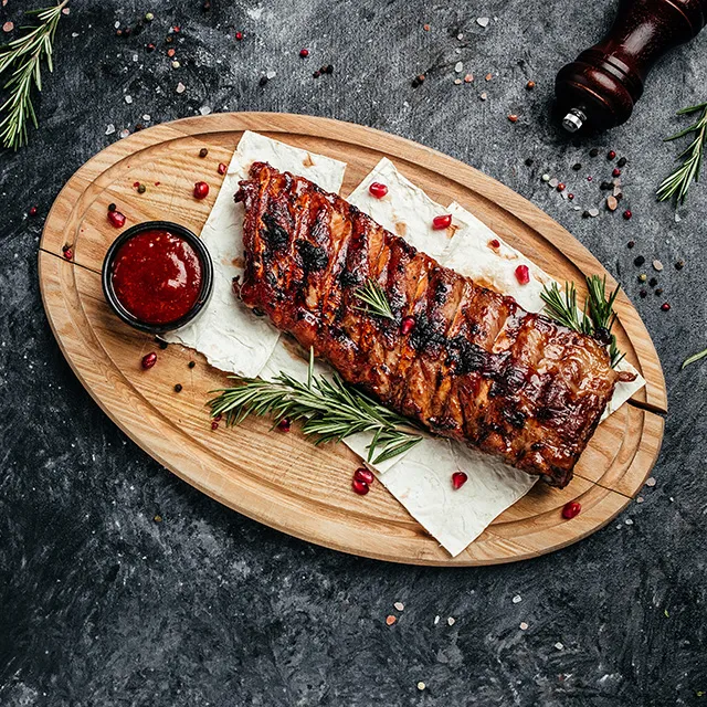 Fruchtige Schweinerippchen auf einem Holzbrett, mit Granatapfelkernen garniert