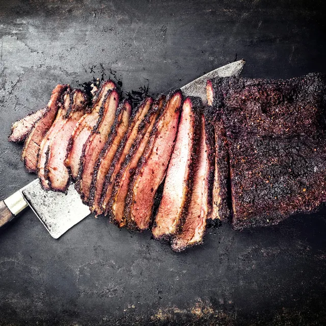 Steak mit Kaffee-Rub, aufgeschnitten auf einem schwarzen Untergrund. Unter dem Steak liegt ein Fleischmesser