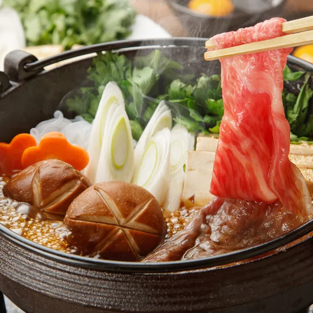 Der japanische Eintopf Sukiyaki, mit frischem Rinderfilet, Nudeln und Chinakohl in einem Topf serviert mit Beilagen.