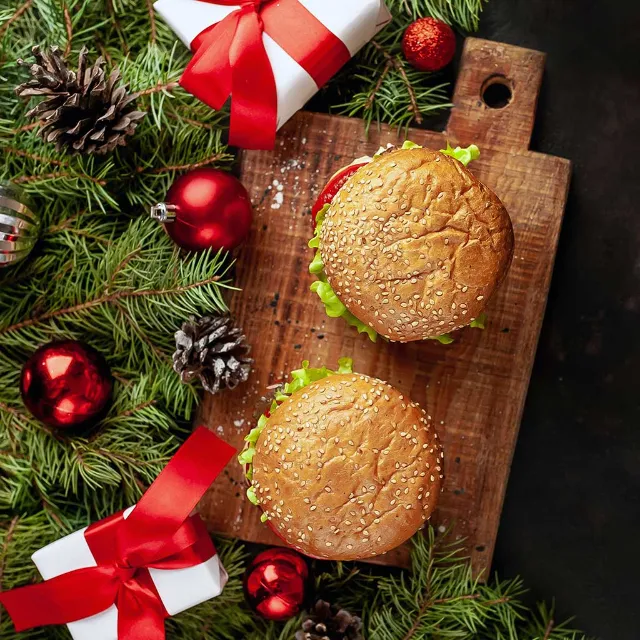 Burger auf einem Holzbrett mit Weihnachtsdeko und kleinen Geschenken