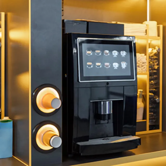 Ein Vollautomat für Kaffee auf einer Theke mit Pappbechern daneben