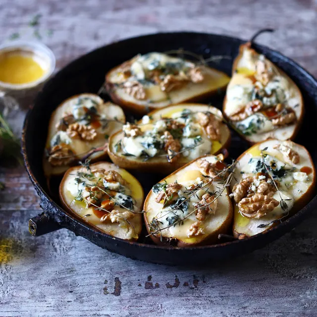 Birnenhälften in einer Auflaufform mit Gorgonzola überbacken und mit Walnüssen garniert