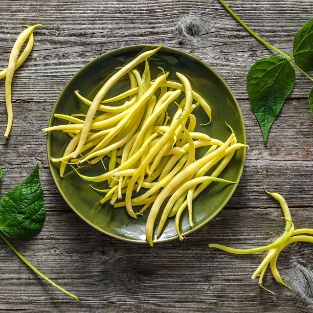 Gelbe Bohnen in einer grünen Schale auf einem Holztisch