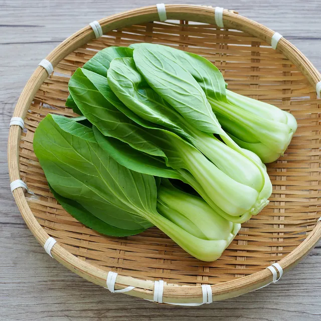 Drei Pak Choi in einem runden Bastkorb