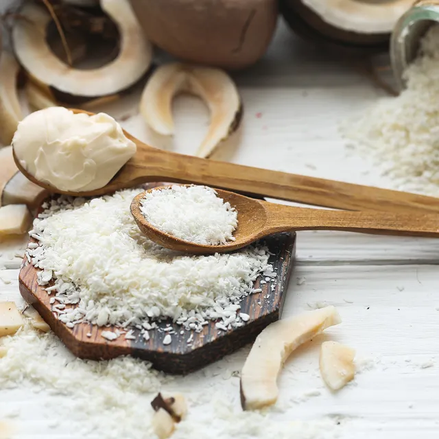 Kokosflocken und Kokosmus auf einem Holzbrett