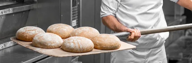 EDEKA-Partner und Produktionsbetriebe - Bäcker, der Brot aus dem Ofen holt.