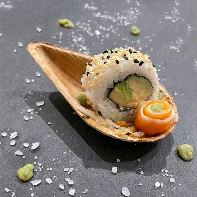 Auf einem Löffel ist ein Stück Sushi angerichtet