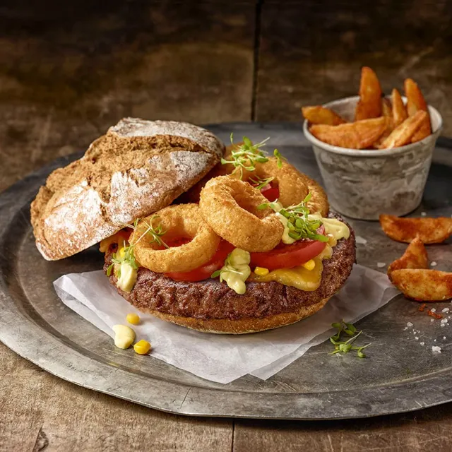 Lecker angerichteter Salomon Giant Burger mit frittierten Zwiebelringen