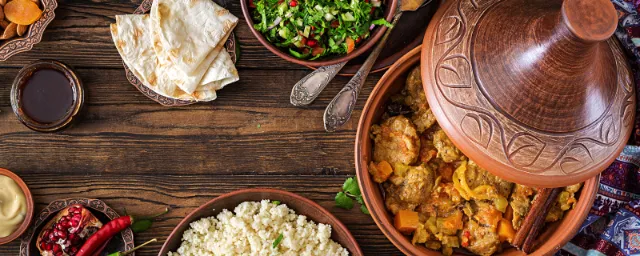 Verschiedene marokkanische Speisen auf einem Holztisch angerichtet mit Tajine.