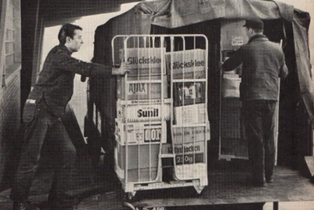 Ein Rollcontainer mit Produkten wird von einem Mitarbeiter in einem Großhandel bewegt.