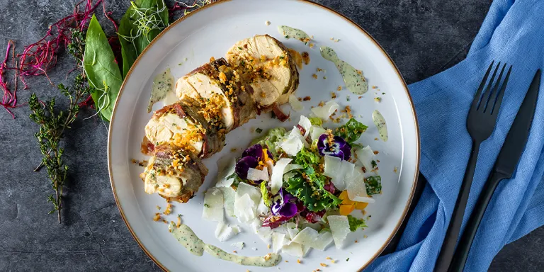 kräutrige hähnchenbrust auf weißem Teller mit Caesar Salad